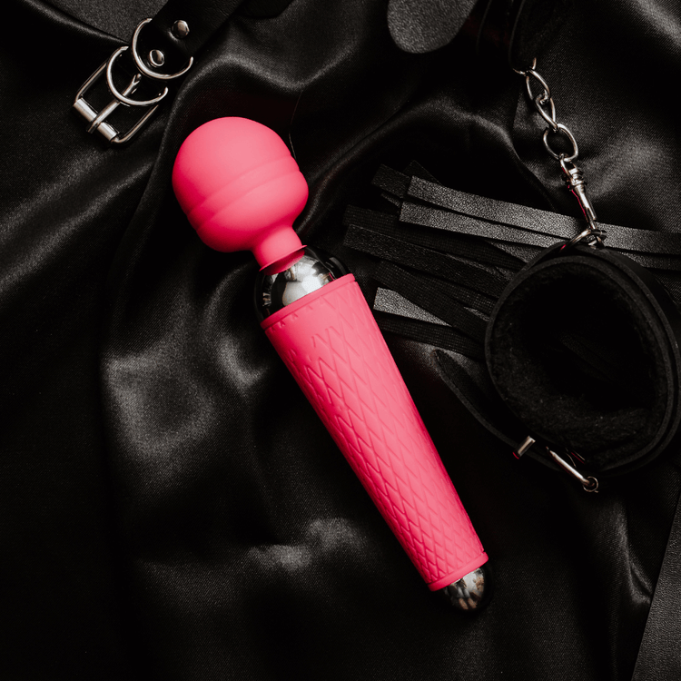 Bright pink vibrator resting on satin fabric, showcasing seamless design for ultimate satisfaction and versatility.