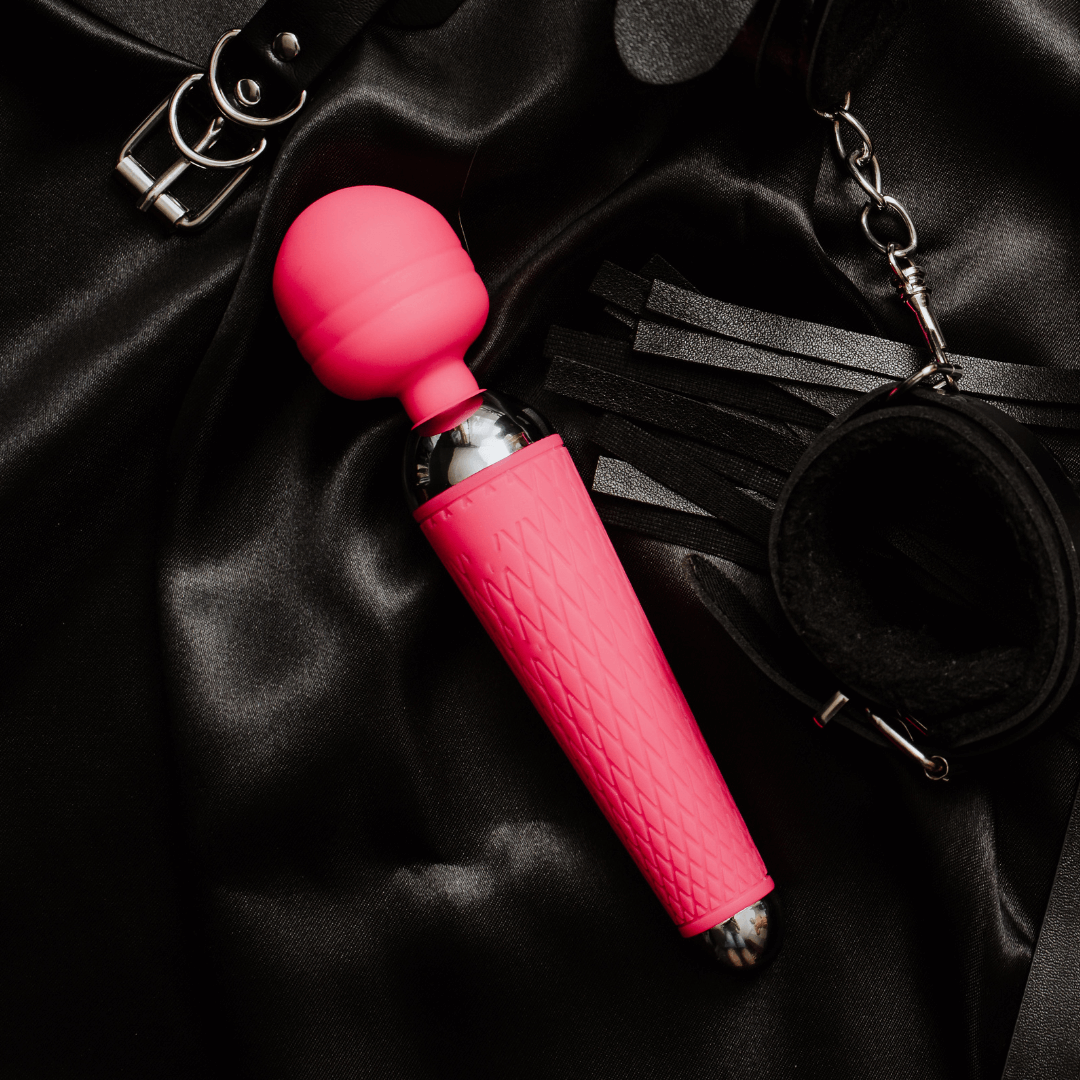 Bright pink vibrator resting on satin fabric, showcasing seamless design for ultimate satisfaction and versatility.