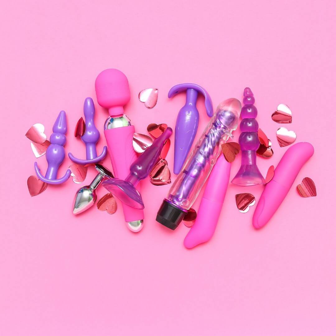 Colorful collection of popular adult toys in shades of pink and purple, featuring hearts on a pink background.