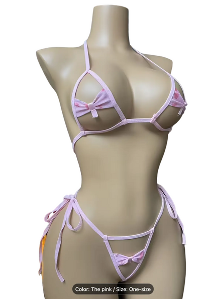 A pink string bikini set displayed on a beige mannequin torso, featuring a triangle bra top with a small bow detail and a matching string thong with side ties and a bow. A Christmas tree and candles are visible on the left against a dark gray background.